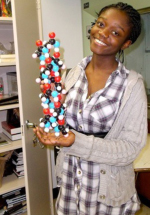 Student Mary Acheampong holding a plastic model of an α-helix, a common 3D motif found in protein structures.