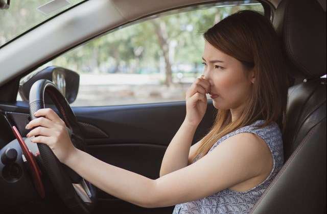 woman in car holding her nose